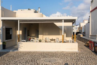 Oia, Santorini Adası, Yunanistan - 18 Eylül 2020: Eski şehrin dar, manzaralı, kaldırım taşı sokağında bir restoran.