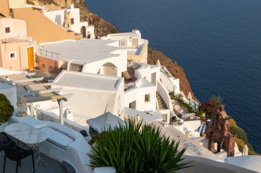Oia, Santorini Adası, Yunanistan - 18 Eylül 2020: Köydeki ünlü, geleneksel kiklodik beyaz mimarinin manzarası. Günbatımı yaşam noktası.
