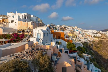 Oia, Santorini Adası, Yunanistan - 18 Eylül 2020: Köydeki ünlü, geleneksel kiklodik beyaz mimarinin manzarası. Günbatımı yaşam noktası.