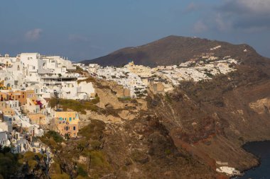 Oia, Santorini Adası, Yunanistan - 18 Eylül 2020: Köydeki ünlü, geleneksel kiklodik beyaz mimarinin manzarası. Günbatımı yaşam noktası.