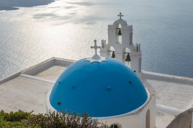 Kutsal Bakire Meryem Katolik Kilisesi 'nin Varsayımı, Üç Zil. Caldera 'nın üzerinde gün batımı manzarası. Fira, Thira, Santorini Adası, Yunanistan.