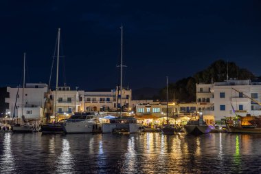 Chora, Ios Adası, Yunanistan 19 Eylül 2020 liman iskelesine demir atmış tekne ve yelkenli gemi. Geceleri limanda beyaz geleneksel binalar. Güzel aydınlatma.