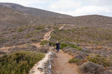 Ios Island, Greece- 20 September 2020: Tourist on the path to the prehistoric tomb of Homer. View of the mountain.