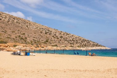 Agia Theodoti Sahili, Ios, Yunanistan - 20 Eylül 2020: İnsanlar Ios 'un en sessiz plajlarından birinde şezlonglarda güneşleniyor. Yunanistan.