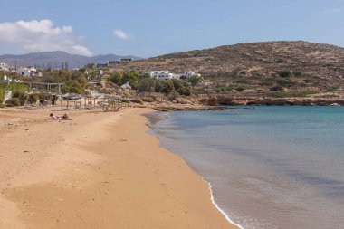 Paralia Koumpara Plajı, Ios, Yunanistan - 20 Eylül 2020: insanlar kumda güneşleniyor ve iskemleler. Geniş, kumlu, palmiye ağaçları olan bir sahil. Yunanistan.