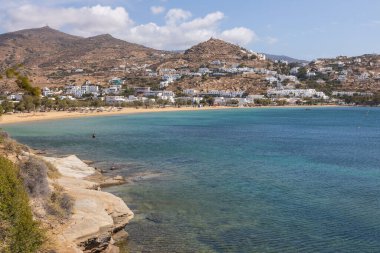 Limandaki geleneksel beyaz binalar, tepedeki Chora ve Ormos Sahili manzarası. Güzel bir yaz günü. Ios Adası, Yunanistan.
