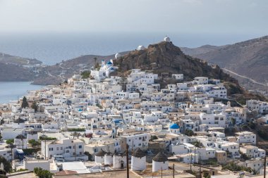 Chora, Ios Island, Greece- 20 September 2020: View of the traditional, white, old buildings in Chora harbor from hill. Beautiful summer day.