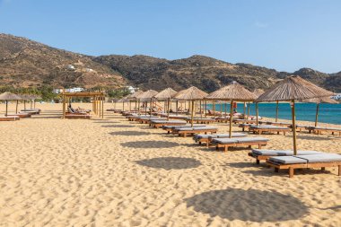 Mylopotas Sahili, Ios Adası, Yunanistan - 20 Eylül 2020: Ios 'un en popüler plajlarından biri. İnsanlar saman şemsiyeler altında güneşleniyorlar..
