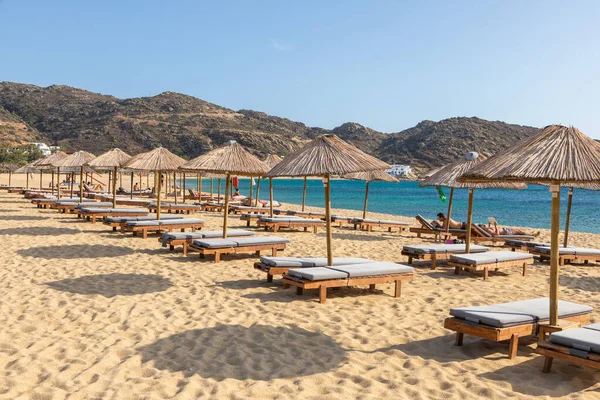 Mylopotas Sahili, Ios Adası, Yunanistan - 20 Eylül 2020: Ios 'un en popüler plajlarından biri. İnsanlar saman şemsiyeler altında güneşleniyorlar..