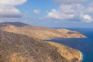 Kıyı şeridi manzarası, dağ manzarası, dolambaçlı yol. Arka planda deniz. Ios Adası, Yunanistan.