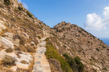 Palaiokastro 'ya giden taş dağ yolu, tepenin üstündeki Bizans kalesini harabeye çeviriyor. Ios Adası, Yunanistan.