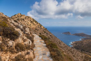 Palaiokastro 'ya giden taş dağ yolu, tepenin üstündeki Bizans kalesini harabeye çeviriyor. Ios Adası, Yunanistan.