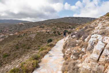 Palaiokastro 'ya giden Taş Dağ yolunda bir kadın, tepedeki Bizans kalesini harabeye çeviriyor. Ios Adası, Yunanistan.