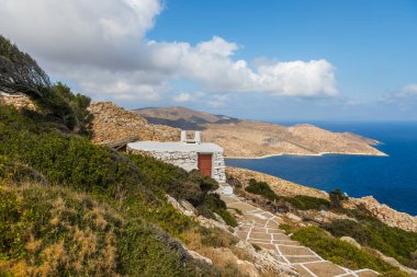 Palaiokastro Kalesi 'nin yanındaki küçük taş binanın manzarası. Ayırt edici beyaz eklemli taş yol. Arka planda kıyı var. Ios Adası, Yunanistan.
