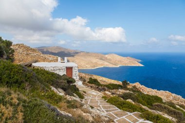 Palaiokastro Kalesi 'nin yanındaki küçük taş binanın manzarası. Ayırt edici beyaz eklemli taş yol. Arka planda kıyı var. Ios Adası, Yunanistan.