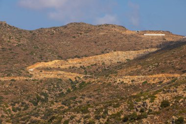 Dağ manzarası, dolambaçlı yol. Tepenin tepesindeki bina. Ios Adası, Yunanistan.