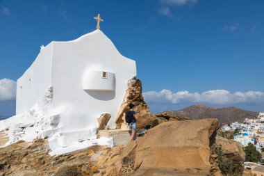 Chora, Ios Adası, Yunanistan 22 Eylül 2020: Eski Chora Kasabası 'ndaki Rock Hill' deki geleneksel beyaz şapelde bir kadın.