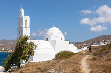 Yunanistan, Ios Adası, Koro- 22 Eylül 2020: Agia Irini, Saint Irene, Yunan Ortodoks Kilisesi, geleneksel beyaz bina yolu üzerindeki insanlar. Güzel yaz güneşli gün.