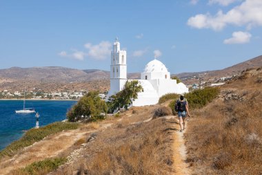 Yunanistan, Ios Adası, Koro- 22 Eylül 2020: Agia Irini, Saint Irene, Yunan Ortodoks Kilisesi, geleneksel beyaz bina yolu üzerindeki insanlar. Güzel yaz güneşli gün.