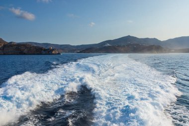 Büyük bir gemi tarafından yapılan Ege Denizi 'nde uyanma. Arka planında geleneksel binalar olan liman. Ios Adası, Yunanistan.