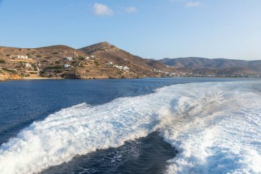 Büyük bir gemi tarafından yapılan Ege Denizi 'nde uyanma. Arka planında geleneksel binalar olan liman. Ios Adası, Yunanistan.