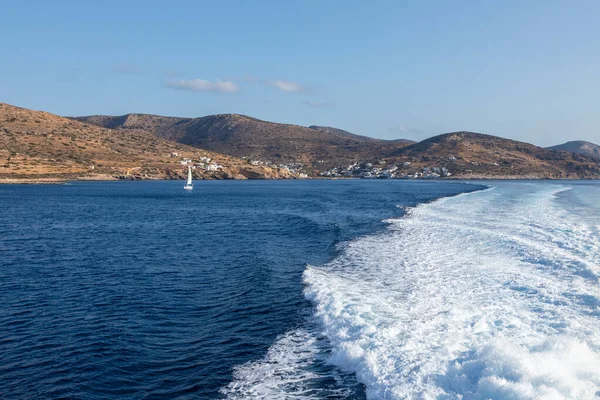 Büyük bir gemi tarafından yapılan Ege Denizi 'nde uyanma. Arka planında geleneksel binalar olan liman. Sikinos Adası, Yunanistan.