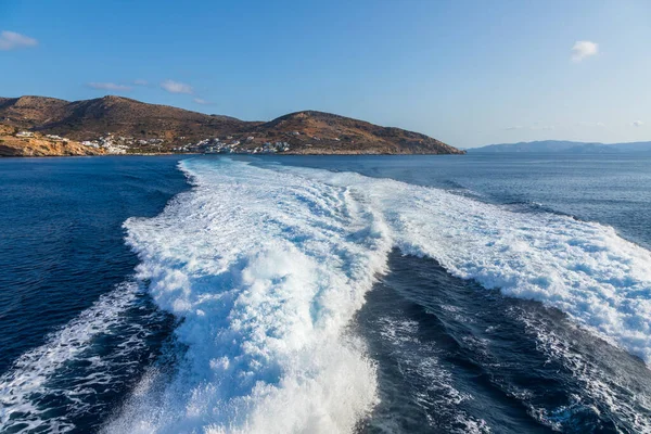Büyük bir gemi tarafından yapılan Ege Denizi 'nde uyanma. Arka planında geleneksel binalar olan liman. Sikinos Adası, Yunanistan.