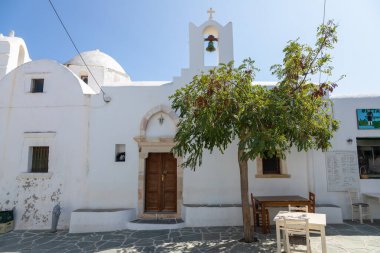 Folegandros Adası, Yunanistan - 23 Eylül 2020: Saint Catherine Kilisesi manzarası. Hemen yanında dışarıda misafirler için masaları olan bir restoran var..