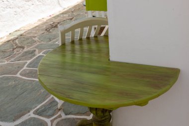 Eski Chora kasabasındaki bir binanın duvarına bitişik yeşil, ahşap bir masa. Folegandros Adası, Yunanistan.