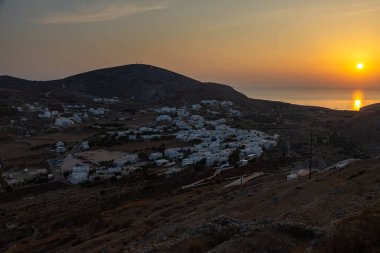 Chora, Folegandros Adası, Yunanistan... 23 Eylül 2020, Chora 'nın üzerinde gün batımı. Geleneksel Yunan binaları ve sahil manzarası.