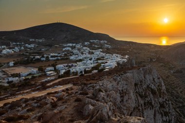 Chora, Folegandros Adası, Yunanistan... 23 Eylül 2020, Chora 'nın üzerinde gün batımı. Geleneksel Yunan binaları ve sahil manzarası.