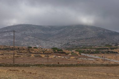 Folegandros Adası, Yunanistan - 24 Eylül 2020: adanın dağlık manzarası, yamaç boyunca kıvrılan yol. Yüksek voltaj sütunları.