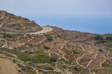 Folegandros adasının kıyı şeridi manzarası. Taş duvarlar yamaçlardan geçerek teraslar oluşturuyor. Cyclades Takımadaları, Yunanistan.