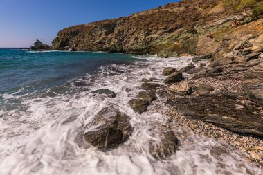 Folegandros Adası, Yunanistan - 25 Eylül 2020: Folegandros adasının kıyı manzarası ve kayalık Ampeli plajı. İnsanlar plajda güneşleniyor. Ege Denizi, Kiklad Takımadası.