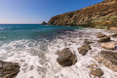 Folegandros Adası, Yunanistan - 25 Eylül 2020: Folegandros adasının kıyı manzarası ve kayalık Ampeli plajı. İnsanlar plajda güneşleniyor. Ege Denizi, Kiklad Takımadası.