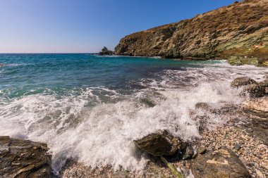 Folegandros Adası, Yunanistan - 25 Eylül 2020: Folegandros adasının kıyı manzarası ve kayalık Ampeli plajı. İnsanlar plajda güneşleniyor. Ege Denizi, Kiklad Takımadası.