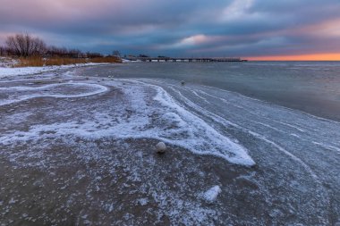 Jastarnia 'da kış manzarası. Gdansk Körfezi sahilinde doğal kar topları. Arka planda iskele var. Güzel gün batımı. Polonya.
