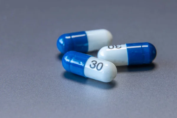 Blue and white tablet pills on a gray background. Healthcare medical.