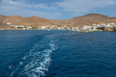 Folegandros Adası, Yunanistan - 26 Eylül 2020: Ege Denizi 'nde uyanma büyük bir gemi tarafından yapıldı. Arka planda geleneksel binalar olan liman.