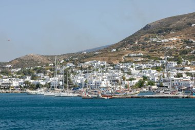 Paros Adası, Yunanistan - 26 Eylül 2020: Arka planda tepelerde geleneksel binalar bulunan liman manzarası.