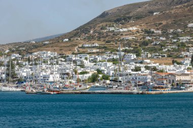 Paros Adası, Yunanistan - 26 Eylül 2020: Arka planda tepelerde geleneksel binalar bulunan liman manzarası.