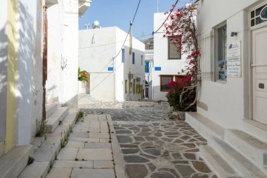 Parikia, Paros Adası, Yunanistan - 26 Eylül 2020: Eski şehrin dar sokakları. Geleneksel, geniş mimari ve beyaz eklemli taş bir yol. Kırmızı Bougainvillea.