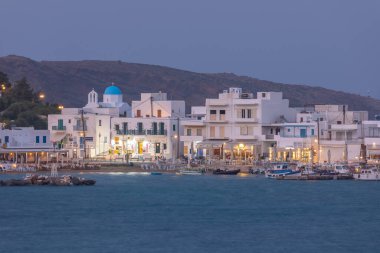 Piso Livadi, Paros Adası, Yunanistan - 26 Eylül 2020: Akşamları geleneksel beyaz binalarla liman manzarası. Aydınlanmalar.