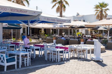 Naoussa, Paros Adası, Yunanistan - 27 Eylül 2020: Yerel restoranları olan liman kentinin ana meydanı. Misafirler için dışarıda masalar.