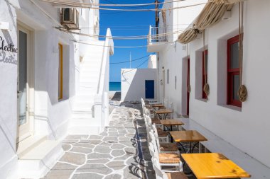 Naoussa, Paros Adası, Yunanistan - 27 Eylül 2020: Yerel restoranı ve dükkanları olan dar balıkçı köyü manzarası. Misafirler için dışarıda masalar.