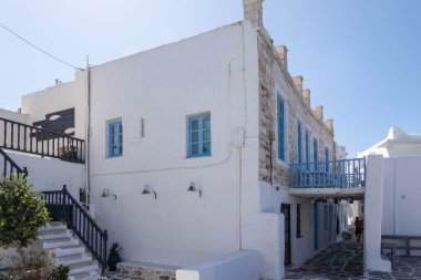 Naoussa, Paros Adası, Yunanistan - 27 Eylül 2020: Balıkçı köyünün dar sokaklarının manzarası. Mavi balkonlu ve panjurlu binaların beyaz cephesi.