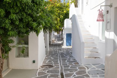 Naoussa, Paros Adası, Yunanistan - 27 Eylül 2020: Balıkçı köyünün dar sokaklarının manzarası. Mavi balkonlu ve panjurlu binaların beyaz cephesi.