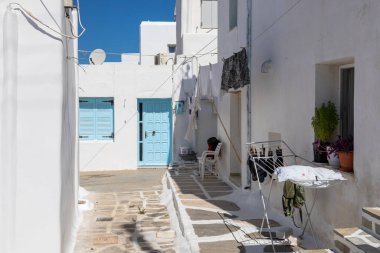 Naoussa, Paros Adası, Yunanistan - 27 Eylül 2020: Balıkçı köyünün dar sokaklarının manzarası. Mavi balkonlu ve panjurlu binaların beyaz cephesi.