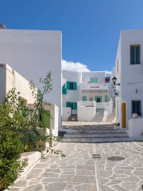 Naoussa, Paros Adası, Yunanistan - 27 Eylül 2020: Balıkçı köyünün dar sokaklarının manzarası. Mavi balkonlu ve panjurlu binaların beyaz cephesi.