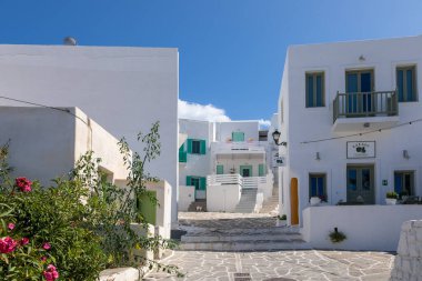 Naoussa, Paros Adası, Yunanistan - 27 Eylül 2020: Balıkçı köyünün dar sokaklarının manzarası. Mavi balkonlu ve panjurlu binaların beyaz cephesi.